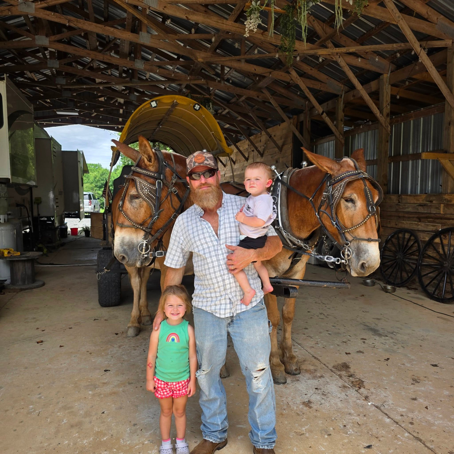 A family standing with Jim and Joe and the wagon inside the barn